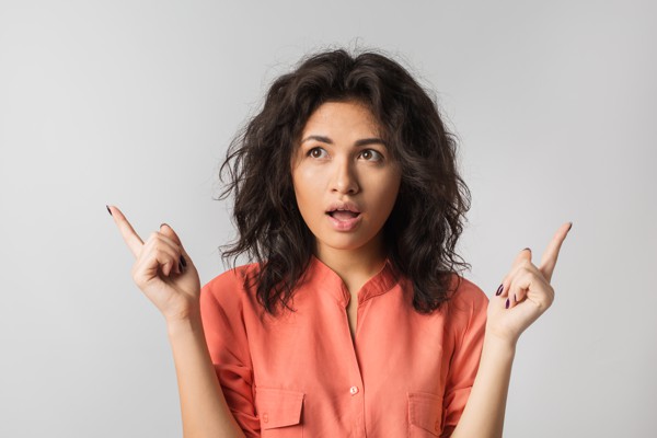 Frau blick fragend, FInger zeigen in zwei Richtungen